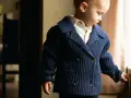 Chłopiec w granatowym sweterku i kremowej koszuli. Pokazuje, jakie kolory do siebie pasują, tworząc elegancką stylizację.