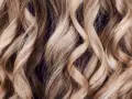 Falujące, jasne blond włosy z subtelnymi refleksami babylights, tworzące efekt muśnięty słońcem.