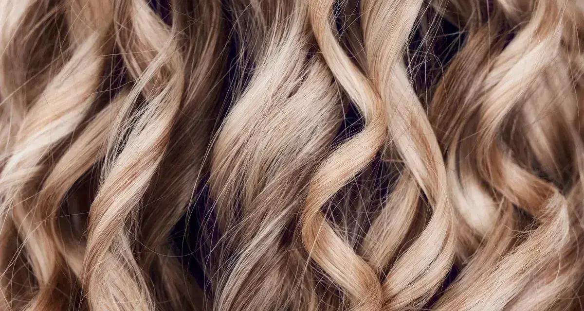 Falujące, jasne blond włosy z subtelnymi refleksami babylights, tworzące efekt muśnięty słońcem.