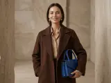 Elegancka kobieta w płaszczu w kolorze czekoladowym z czym łączyć? Z błękitną torebką i złotymi kolczykami.