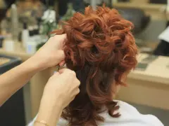 Tworzenie fryzury z rudymi, kręconymi włosami. Upięcia w trakcie stylizacji.