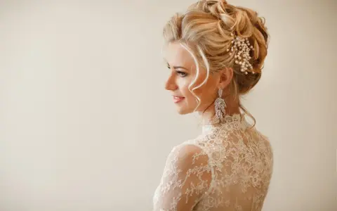 Elegancka fryzura wieczorowa z perłami i kryształowymi kolczykami. Delikatne loki opadają na ramiona.