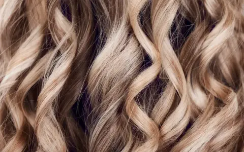 Falujące, jasne blond włosy z subtelnymi refleksami babylights, tworzące efekt muśnięty słońcem.