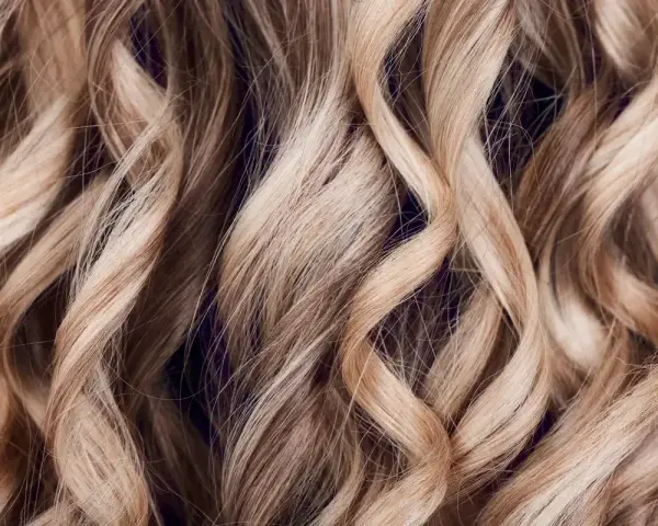 Falujące, jasne blond włosy z subtelnymi refleksami babylights, tworzące efekt muśnięty słońcem.