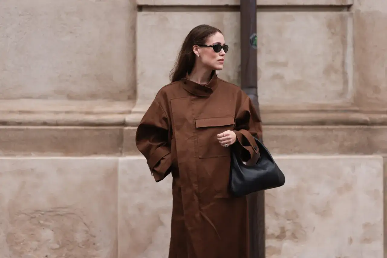 Elegancka kobieta w płaszczu w kolorze czekoladowym z czarną torebką. Ten odcień świetnie komponuje się z czernią, tworząc wyrafinowany look.