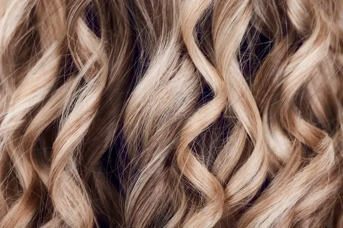 Delikatne babylights na falowanych, blond włosach, tworzące subtelny efekt muśnięcia słońcem.